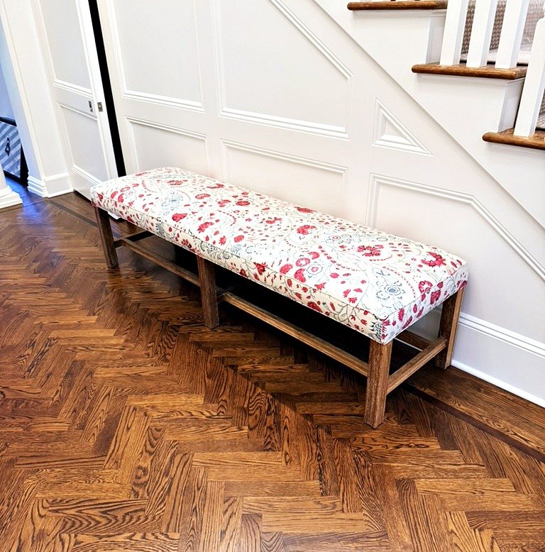 Upholstered bench in a red and blue floral fabric in a hallway