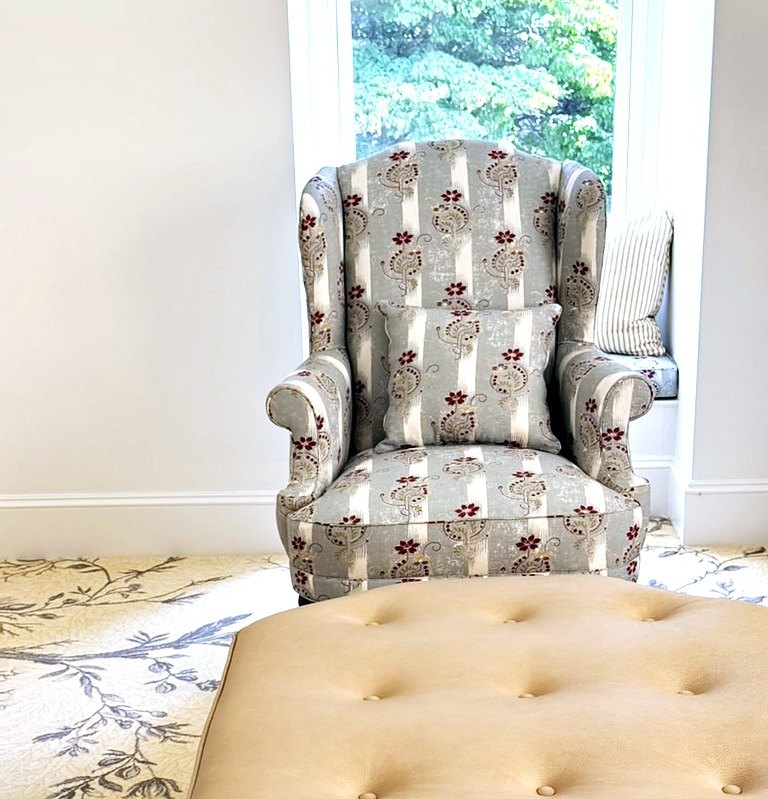 Wing chair reupholstered in a striped floral fabric, by a window